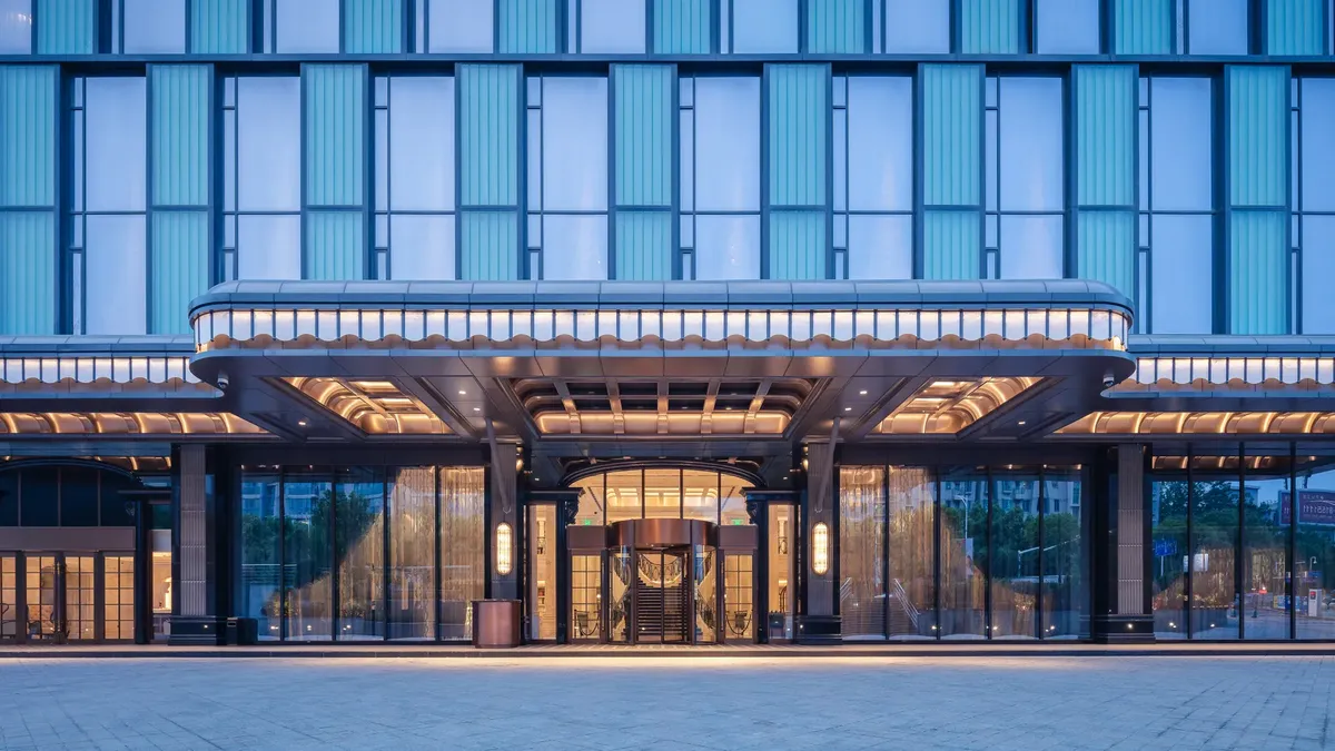 Elegant modern hotel entrance with glass facade and ambient lighting.