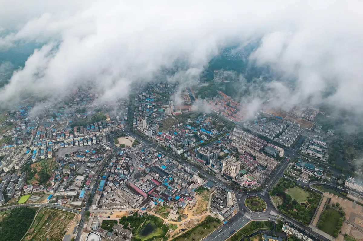 Aerial photograph capturing a bustling city in China partially covered with clouds.
