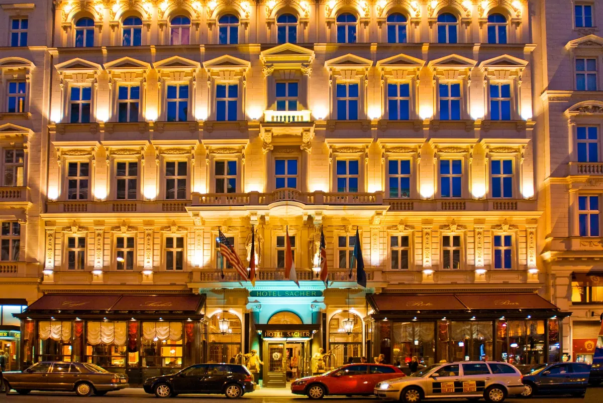 Elegant Hotel Sacher facade illuminated at night with street view in Vienna, Austria.