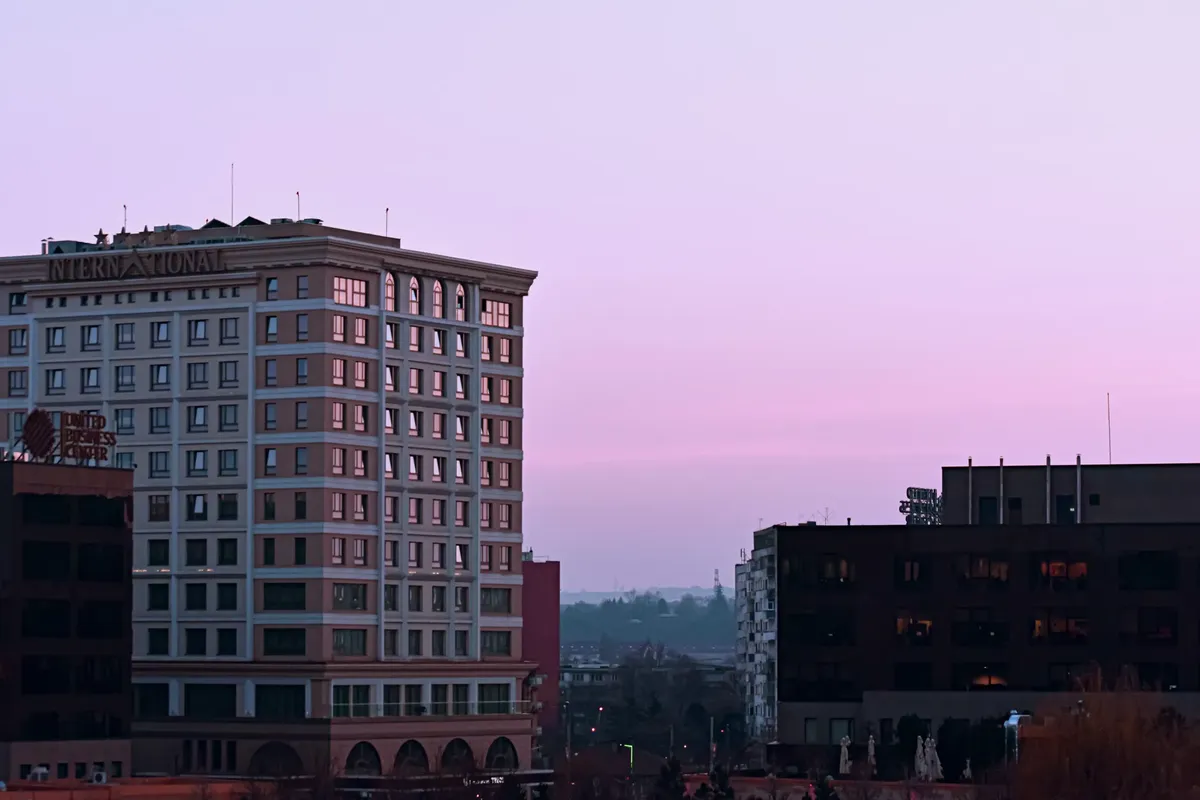 Modern international four star hotel complex surrounded by business centers at colorful sunset in downtown of megapolis